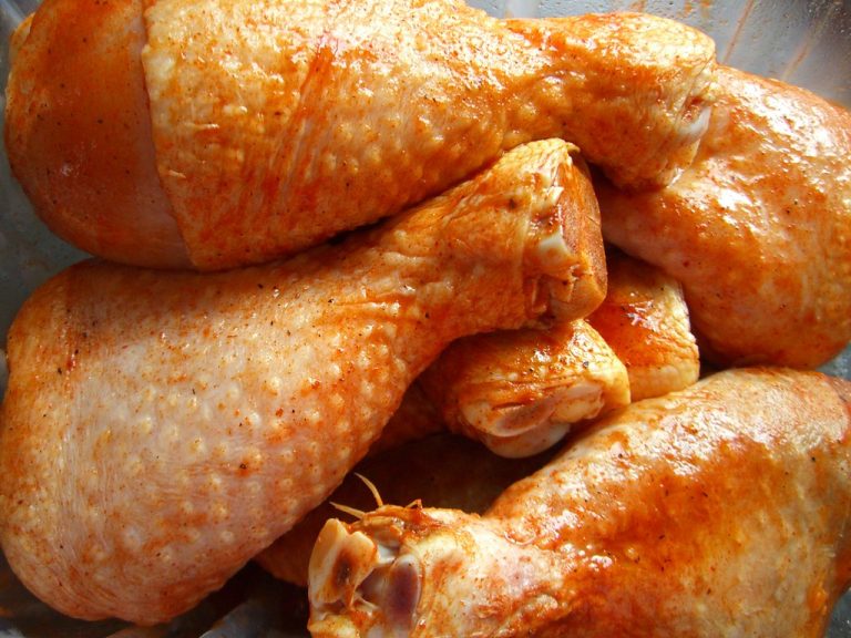 Raw chicken breasts, thighs, drumsticks, and wings arranged on a wooden cutting board.