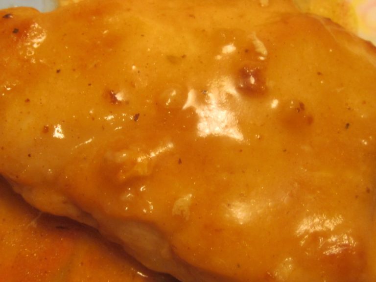 Glossy pan sauce being spooned over a seared chicken breast in a skillet