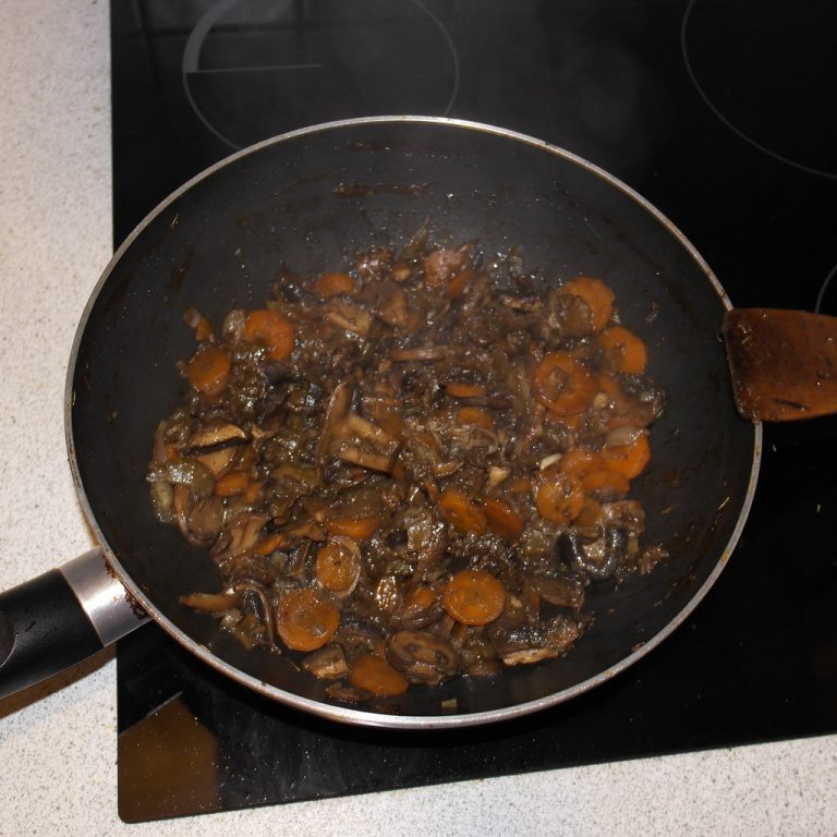 Pot of simmering homemade chicken stock with vegetables and a skimming ladle