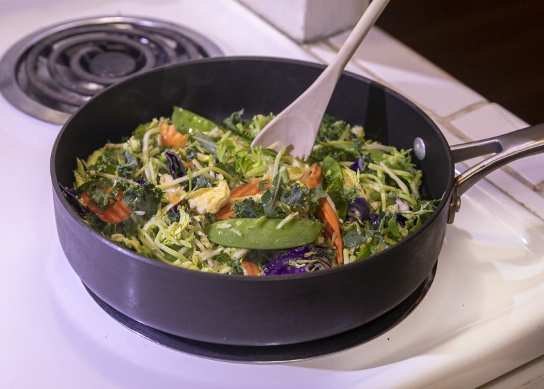 Sliced zucchini, bell pepper, and mushrooms being sauteed in a wide skillet over high heat with browned edges forming.