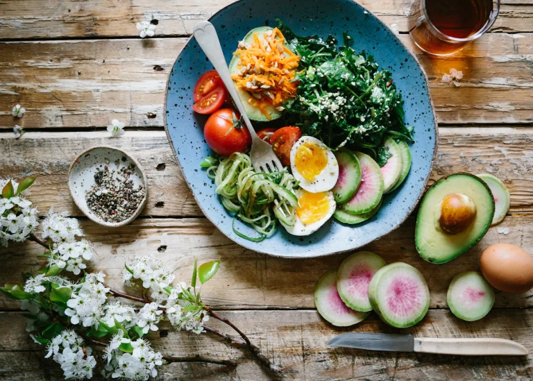 A bowl of greens topped with avocado and egg.