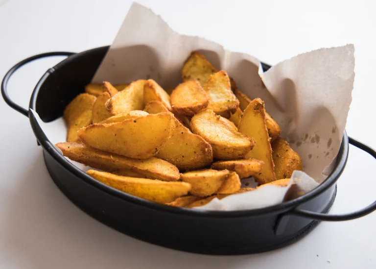 Golden roasted potato wedges in a dark pan.