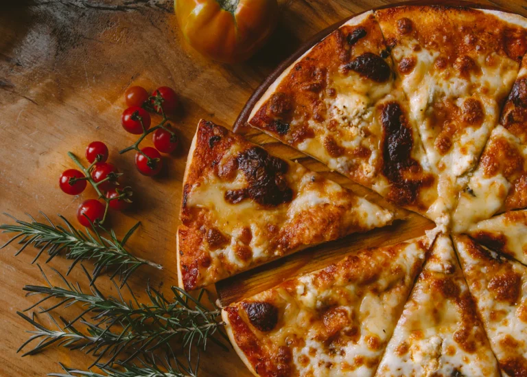 A baked pizza topped with cheese, tomato and herbs.