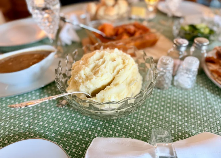A serving bowl of creamy mashed potatoes on a dinner table.