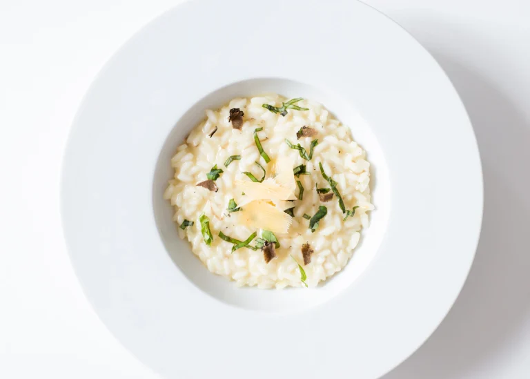 A bowl of mushroom risotto garnished with herbs.